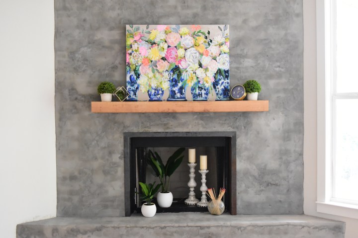 bright floral painting on modern concrete fireplace.