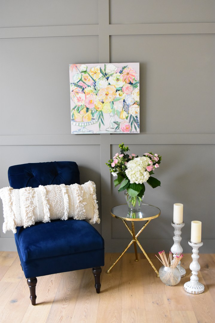 bright floral painting with pears paired with blue velvet chair and white candlesticks.